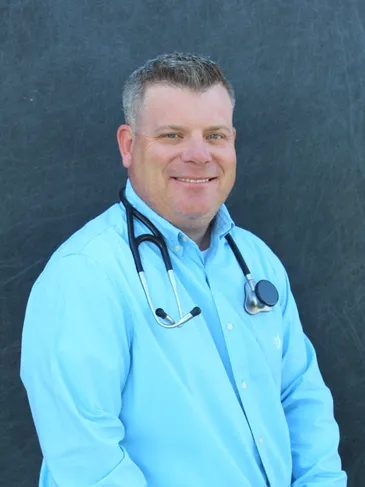 A man with stethoscope standing in front of a wall.